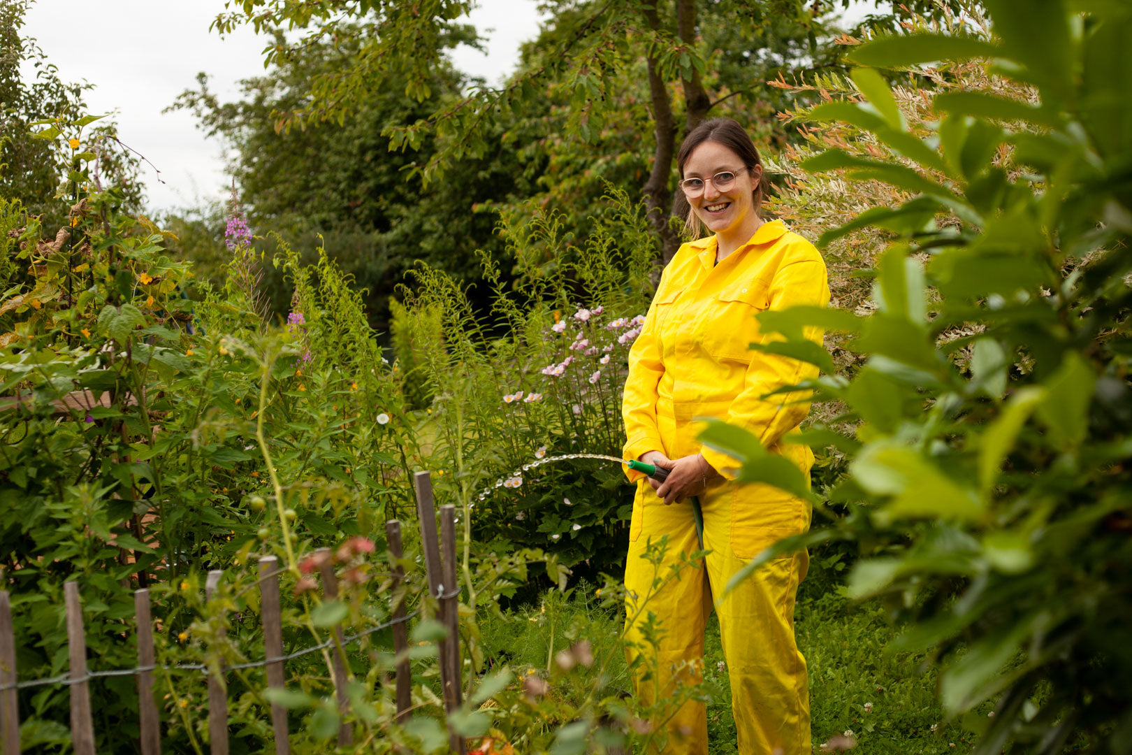  Tanja hält Gartenschlauch vor sich