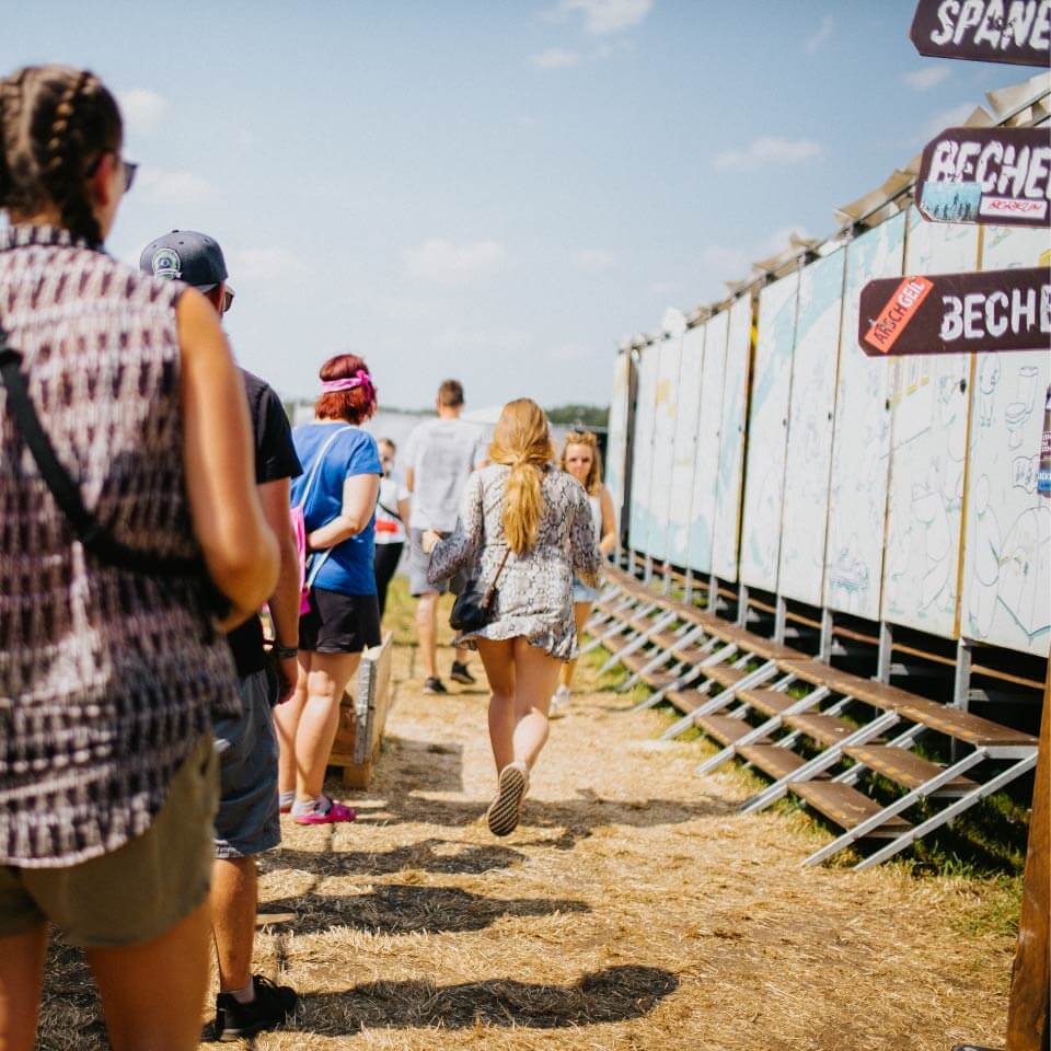 Menschen stehen vor Goldeimer Trockentoiletten auf einem Festival